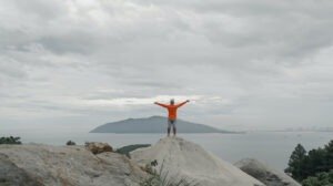 man standing on a hill with arms outstretched